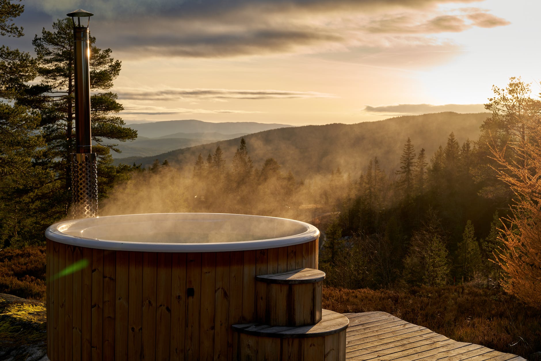 a hot tub with a view of a forest and a mountain range